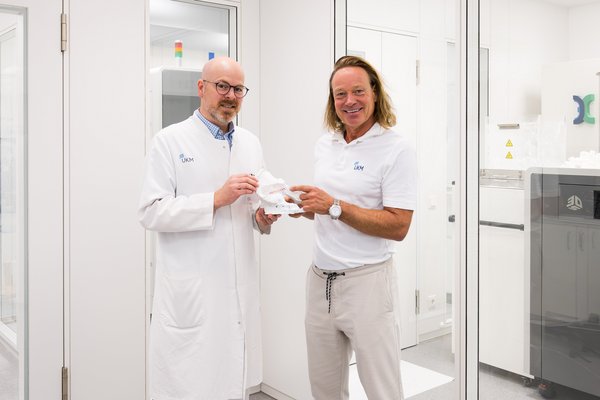UKM | Die Klinikdirektoren der Unfallchirurgie und der Orthopädie halten ein anatomisches Modell in den Händen und lachen in die Kamera.