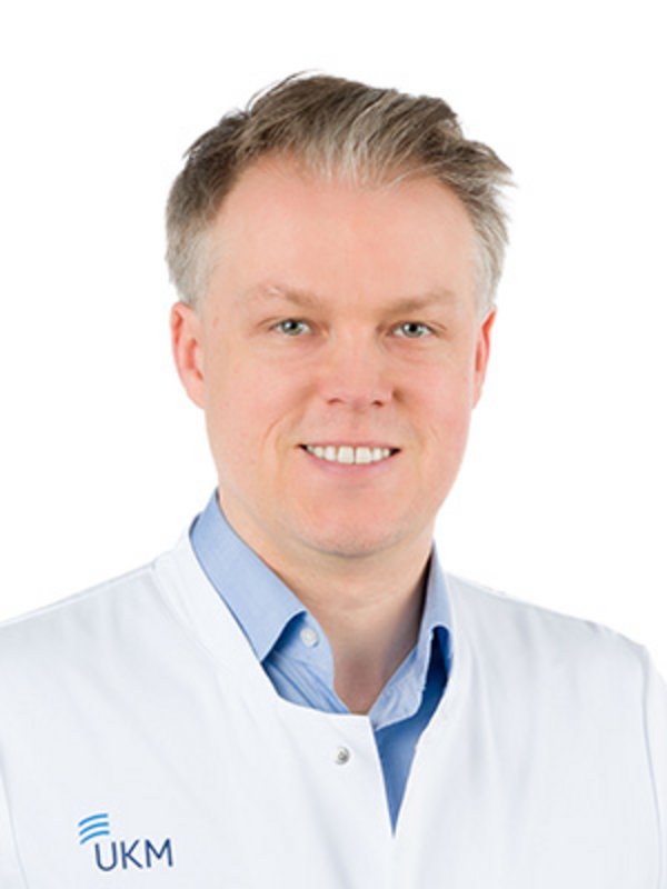 UKM | Arzt der Medizinischen Klinik A. Er trägt einen weißen Kittel und lächelt.