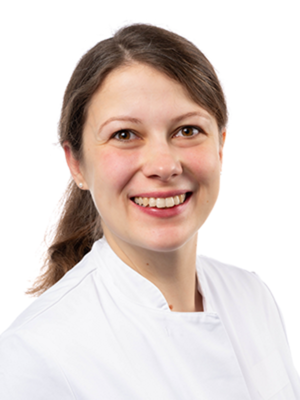 UKM | Zahnärztin der Klinik für Parodontologie. Sie trägt einen weißen Kittel und lacht.