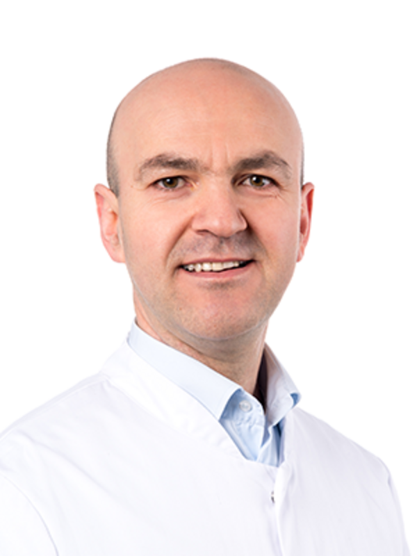 UKM | Fachzahnarzt für Parodontologie. Er trägt einen weißen Kittel und lächelt.