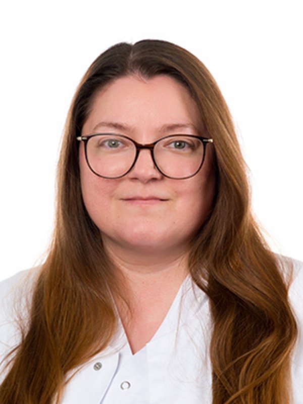 UKM Nuklearmedizin | Sibel Selina Dehn | Sie hat braune lange Haare, trägt eine Brille und schaut in die Kamera.