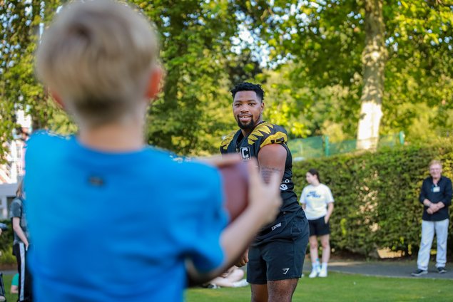 Keegan McCormack-Reamer wirft einem Kind einen Football zu.