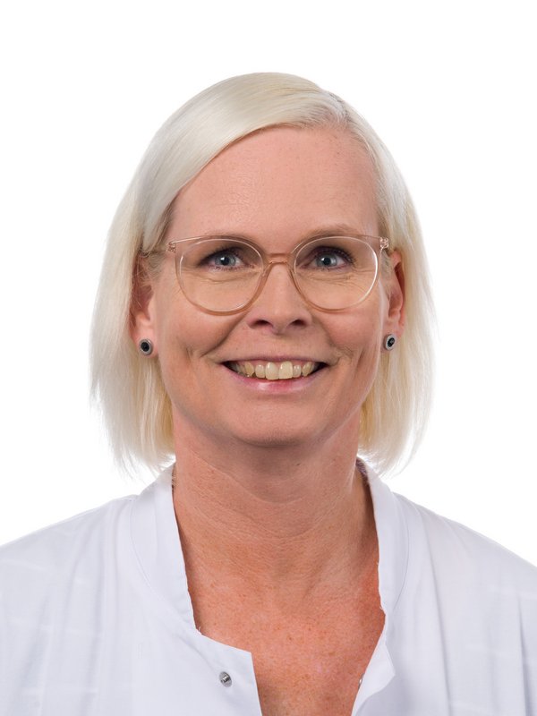 Frau im weißen Kittel, die lächelt.