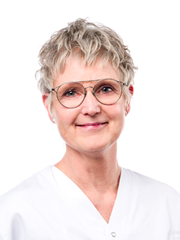 UKM | Portraitaufnahme einer Dentalhygienikerin der Klinik für Parodontologie. Sie trägt eine Brille, einen weißen Kasack und lächelt.