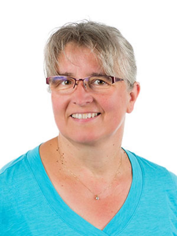 UKM Pädiatrische Hämatologie und Onkologie | Monika Poeppelmann | Sie trägt ein blaues T-Shirt, eine Brille und lächelt in die Kamera.
