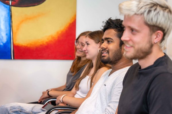 Vier neue Auszubildende am UKM hören amüsiert bei der Begrüßungsveranstaltung zu.