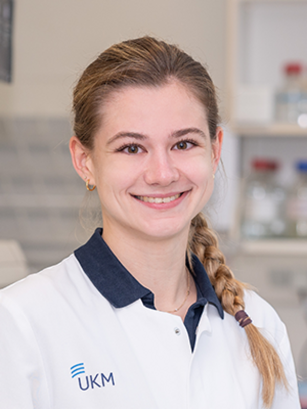 UKM | Portraitaufnahme einer Mitarbeiterin im Forschungsteam der Klinik für Endovaskuläre und Vaskuläre Chirurgie | Sie trägt einen weißen Kittel und lächelt