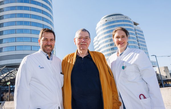 Klinikdirektor und Ärztin der Medizinischen Klinik B mit einem Patienten. Im Hintergrund die beiden Bettentürme des UKM