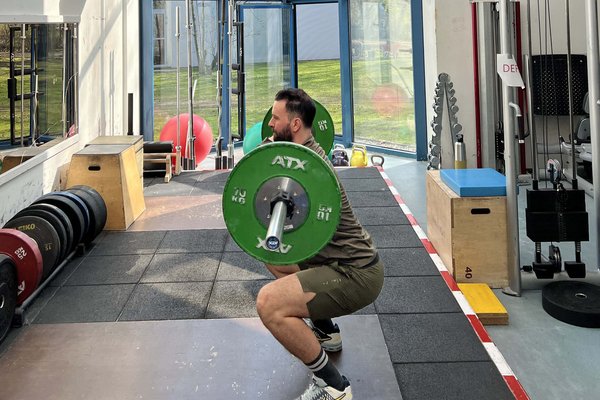 UKM | Pressefoto | Mann in Sportkleidung beim Gewichtheben im Trainingsraum.