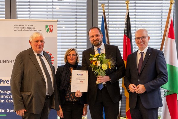 UKM | Presse | Preisträger mit Urkunde und Blumenstrauß sowie Vertreter des Landes Nordrhein-Westfalen