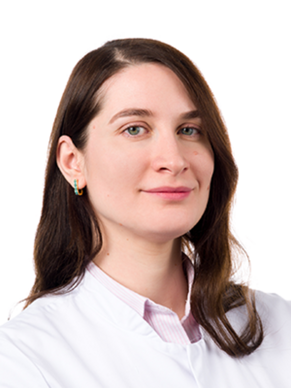 UKM | Portraitaufnahme einer Ärztin aus der Gefäßchirurgie. Sie trägt einen weißen Kittel und lächelt.