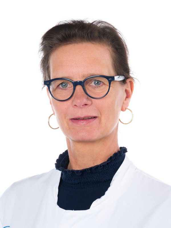 Frau in weißem Kittel, die lächelt.