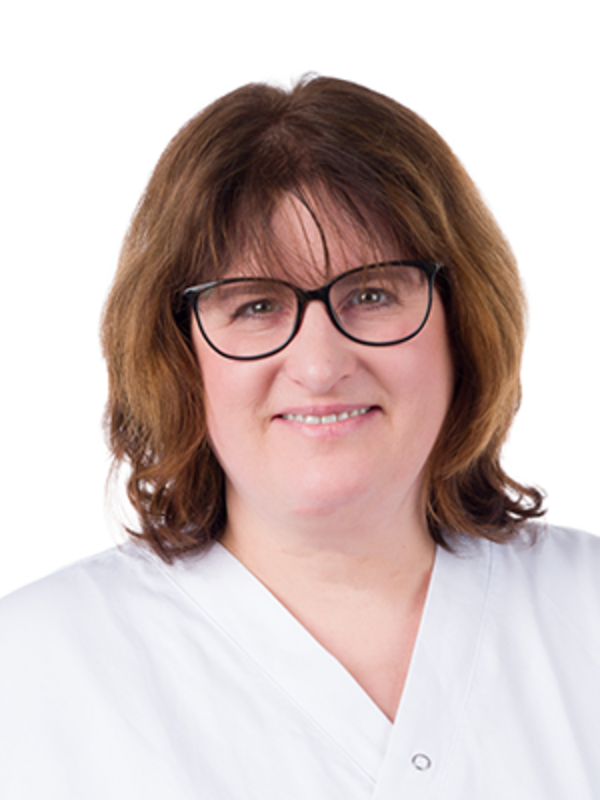 UKM | Dentalhygienikerin in der Parodontologie. Sie trägt einen weißen Kasack und lächelt.