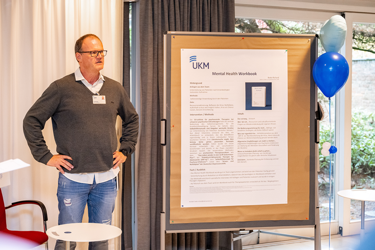 UKM | Magnet-Projekt Best Practice Forum | Ein Vortragender steht vor einem Plakat.