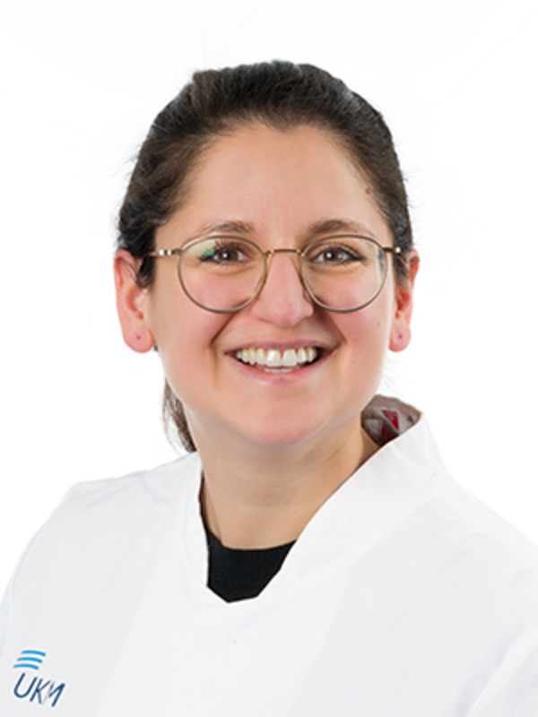 UKM | Zahnärztin der Klinik für Parodontologie. Sie trägt einen weißen Kittel und lacht.