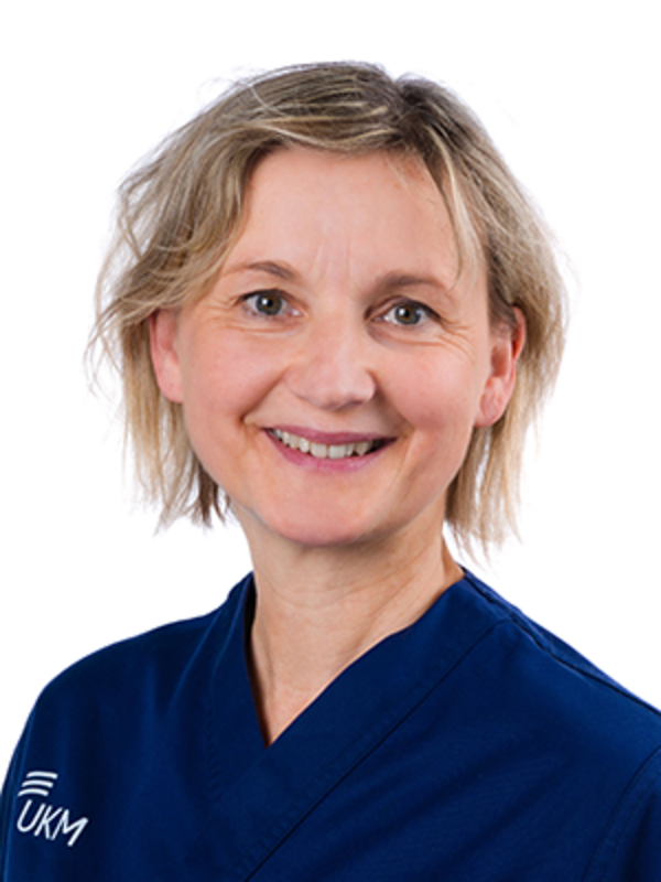 UKM | Mitarbeiterin der Unfallchirurgie. Sie trägt einen dunkelblauen Kasack und lächelt.