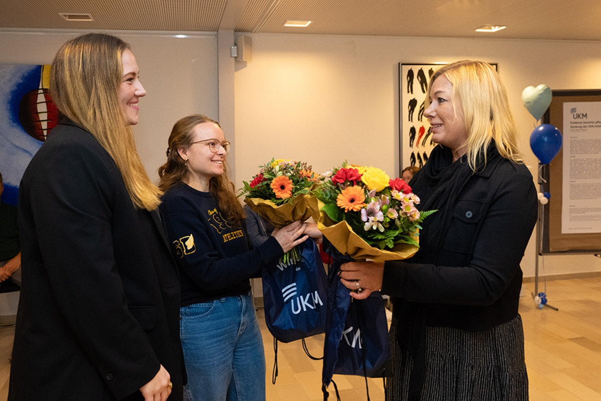 UKM | Magnet-Projekt Best Practice Forum | Die stellvertretende Pflegedirektorin Stephanie Krähe überreicht zwei Referentinnen jeweils einen bunten Blumenstrauß.