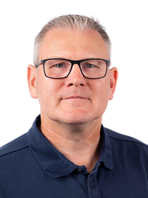 UKM Werkfeuerwehr | Portraitbild von Marc Brüner | Er trägt eine dunkle Brille, ein dunkelblaues T-Shirt und schaut in die Kamera.
