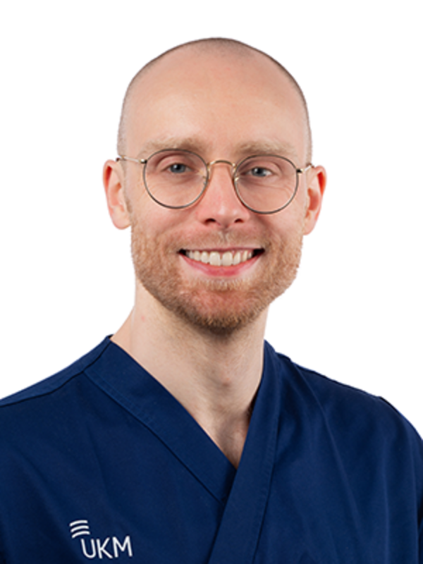 UKM | Arzt der Unfallchirurgie. Er trägt einen dunkelblauen Kasack und lächelt.