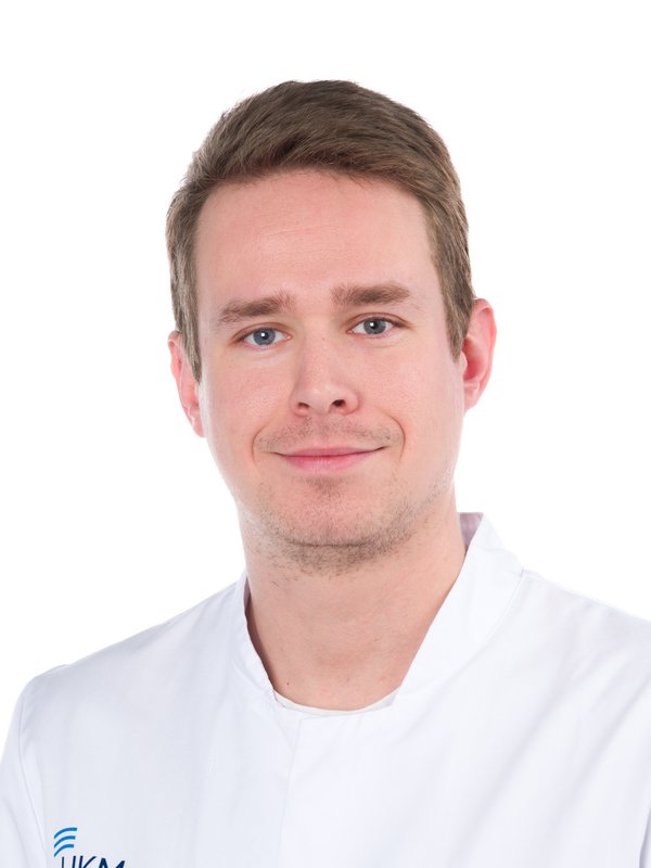 Mann in weißem Kittel, der lächelt.