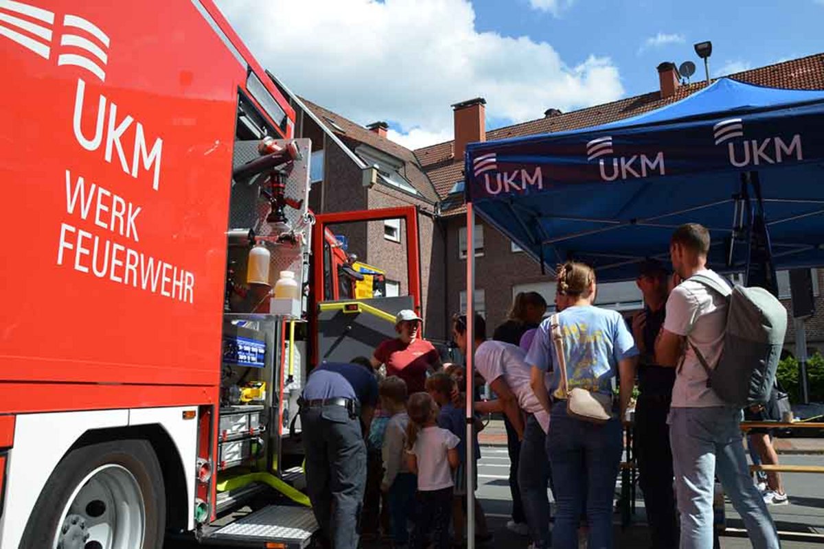 UKM Werkfeuerwehr | Man sieht Menschen die in einen Feuerwehrwagen schauen und drumherum stehen.
