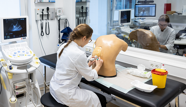 UKM | Studentin übt mit einem Gerät an einem künstlichen Torso