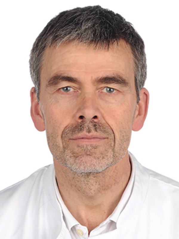 UKM Pädiatrische Hämatologie und Onkologie | Andreas Groll | Trägt ein weißes Shirt und schaut in die Kamera.