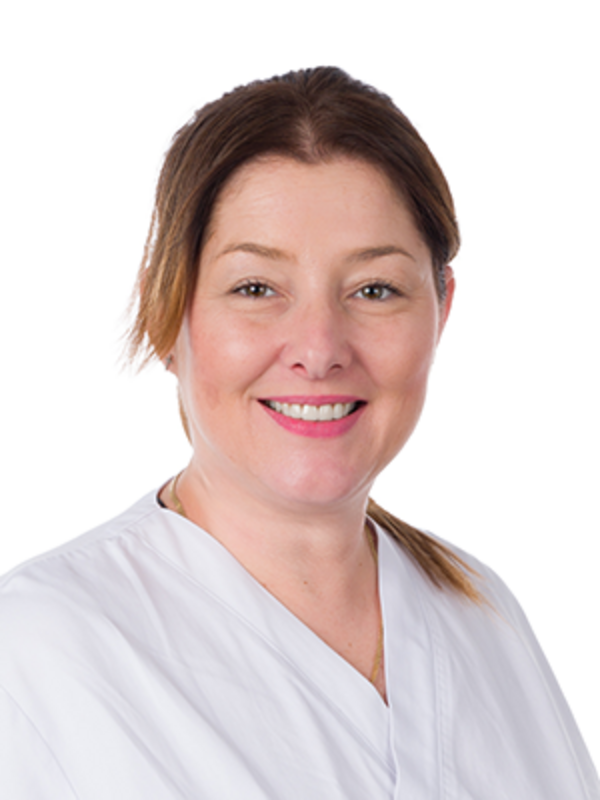 UKM | Dentalhygienikerin der Klinik für Parodontologie. Sie trägt einen weißen Kasack und lächelt.