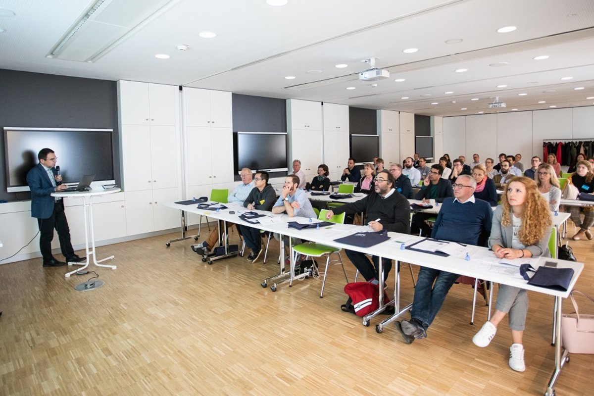 UKM Herz-MRT-Zentrum | Teilnehmende sitzen an Tischen und hören sich einen Vortrag an.