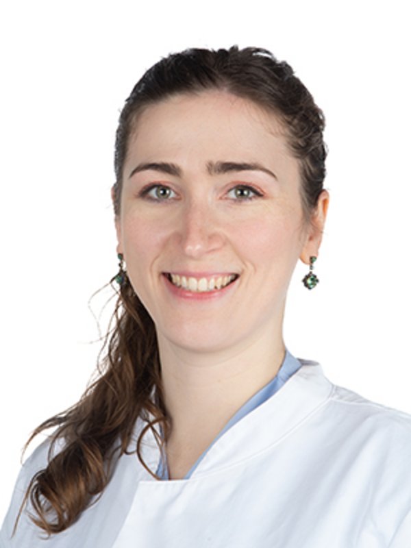 UKM Medizinische Klinik D | Nathalie Becker | Sie hat braune Haare, trägt einen weißen Kittel und lächelt in die Kamera.
