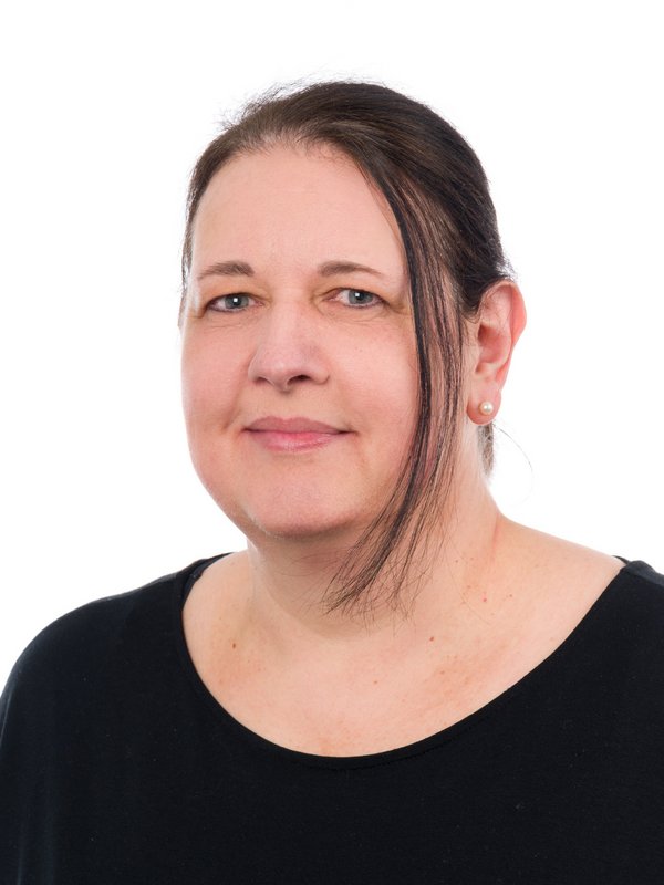 Frau in dunklem Oberteil, die lächelt.