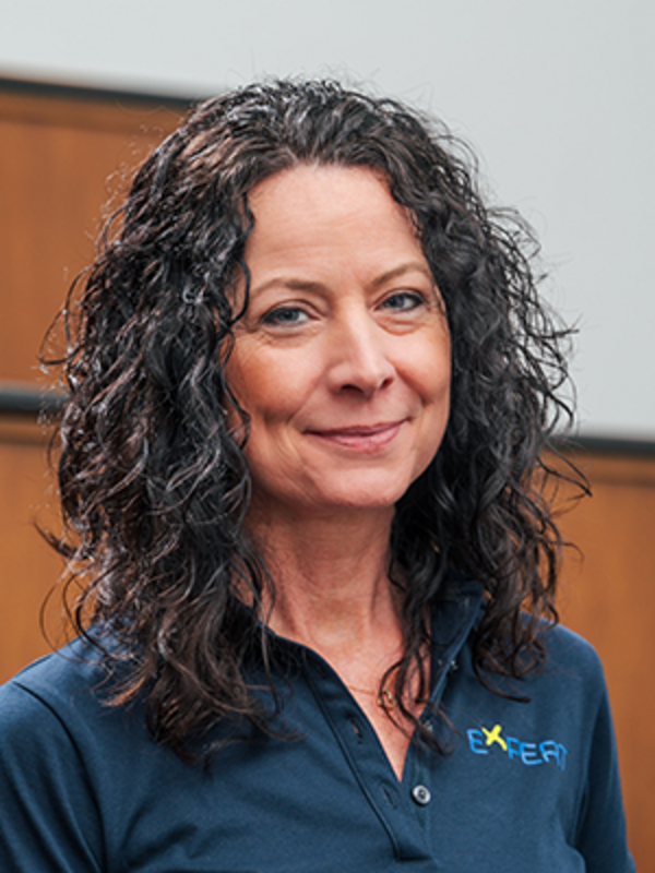 UKM | Portrait einer Mitarbeiterin des Expert-Projekts. Sie trägt ein dunkelblaues Poloshirt und lächelt.