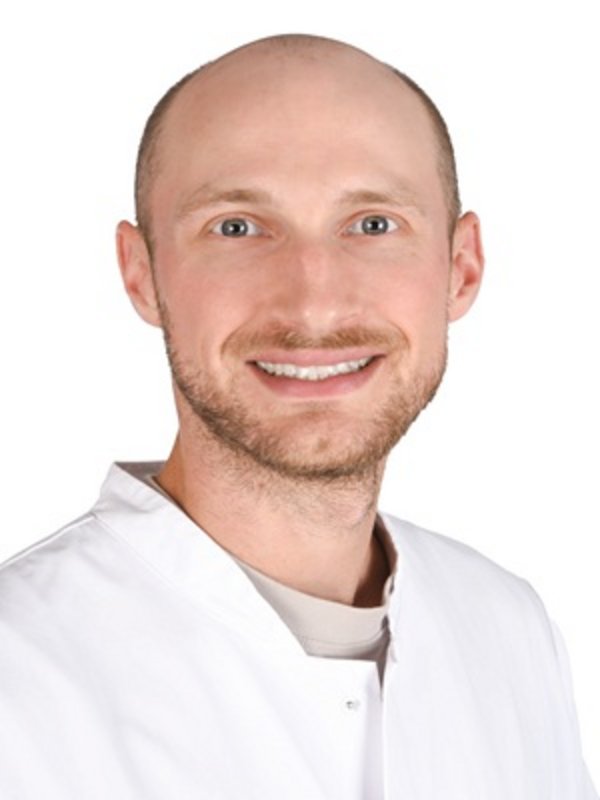 UKM Prurituszentrum | Mann mit weißem Kittel lächelt in die Kamera.