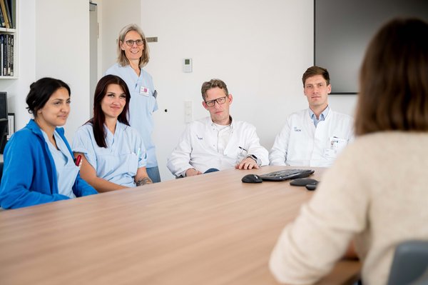UKM | Presse | Zwei Ärzte und drei Pflegerinnen mit genesener Patientin an einem Tisch
