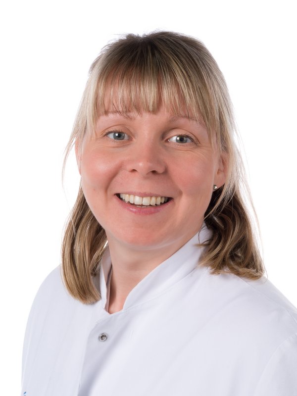 Frau im weißen Kittel, die lächelt.