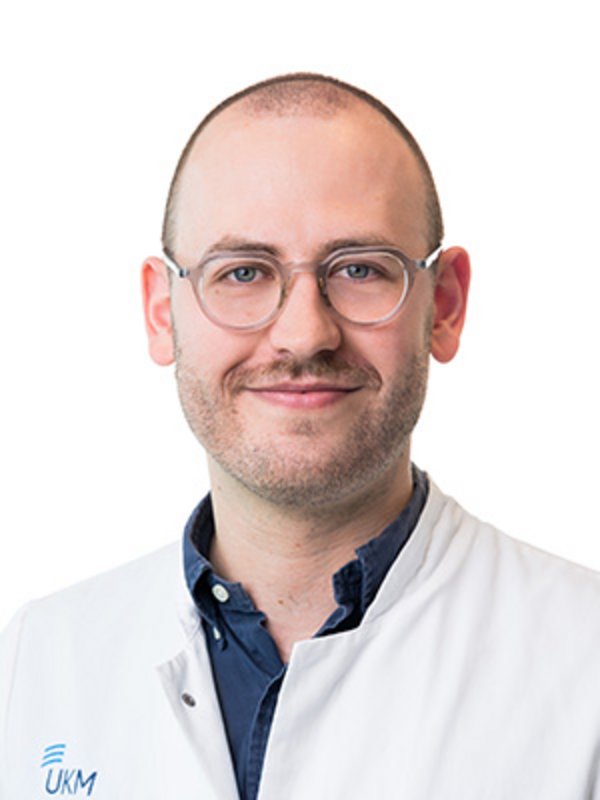 UKM Plastische Chirurgie | Felix Ruhl | Mann mit Brille lächelt in die Kamera.