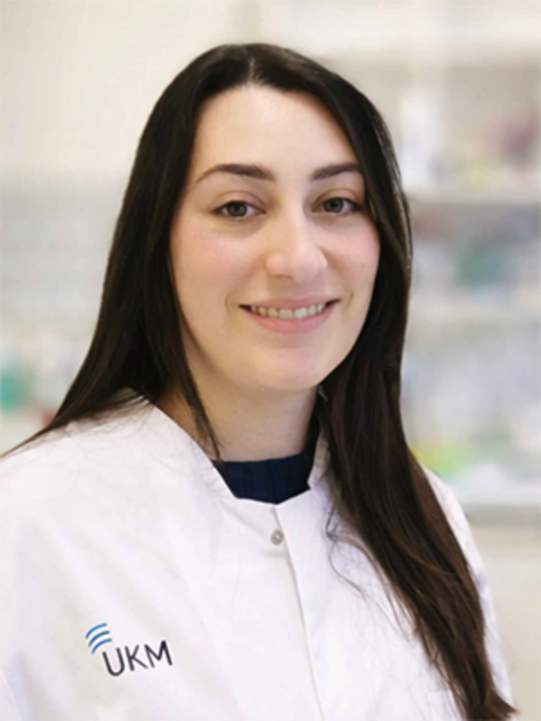 UKM | Labormitarbeiterin im Forschungsteam der Gefäßchchirurgie. Sie trägt einen weißen Kittel und lächelt.