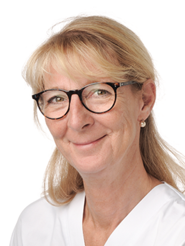 UKM | Portrait einer Zahnmedizinischen Prophylaxeassistentin der Klinik für Parodontologie. Sie trägt eine Brille, einen weißen Kasack und lächelt.