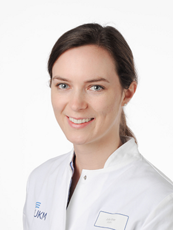 UKM | Portrait einer Ärztin aus der Angiologie. Sie trägt einen weißen Kittel und lächelt.