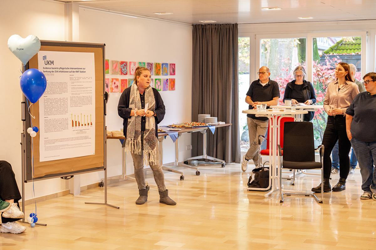UKM | Beim Magnet-Projekt Best Practice Forum steht eine Vortragende vor einem Plakat, Teilnehmende stehen an Stehtischen.