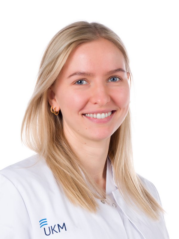 Frau im weißen Kittel, die lächelt.