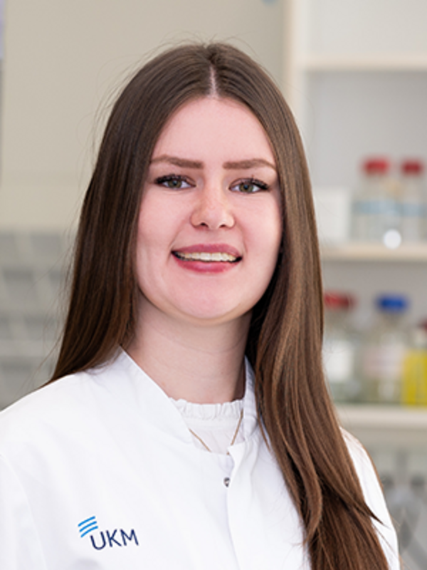 UKM | Portraitaufnahme einer Mitarbeiterin im Forschungsteam der Klinik für Endovaskuläre und Vaskuläre Chirurgie | Sie trägt einen weißen Kittel und lächelt