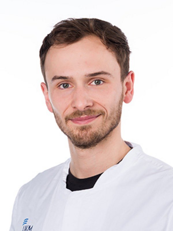 UKM Klinik für Nuklearmedizin | Ole Platte | Er trägt einen weißen Kittel und lächelt in die Kamera.
