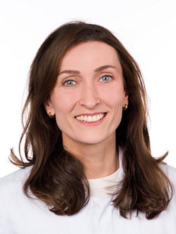 UKM | Zahnärztin aus der Klinik für Parodontologie. Sie trägt einen weißen Kittel und lacht.