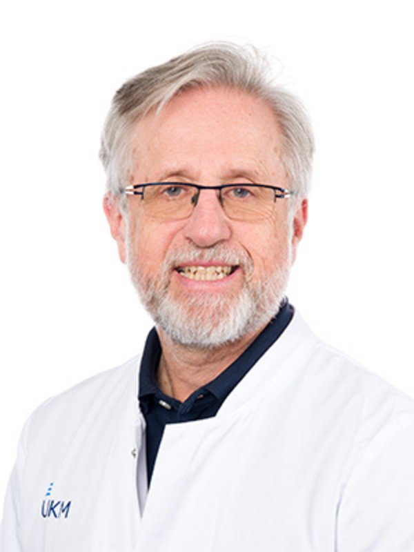 UKM | Arzt aus dem Alterstraumazentrum. Er trägt einen weißen Kittel und lächelt.
