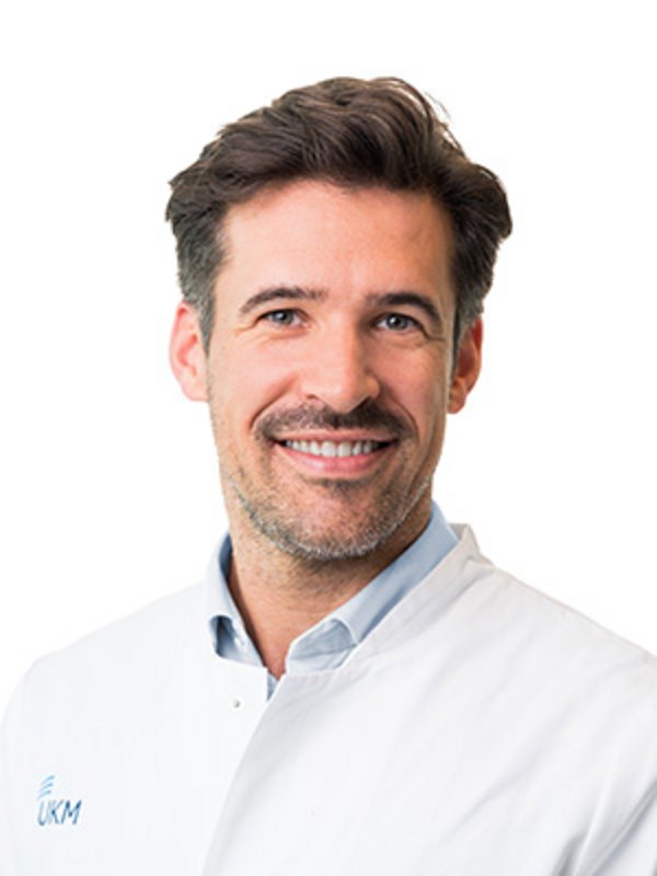 UKM Plastische Chirurgie | Philipp Wiebringhaus | Mann mit braunen Haaren lächelt in die Kamera.