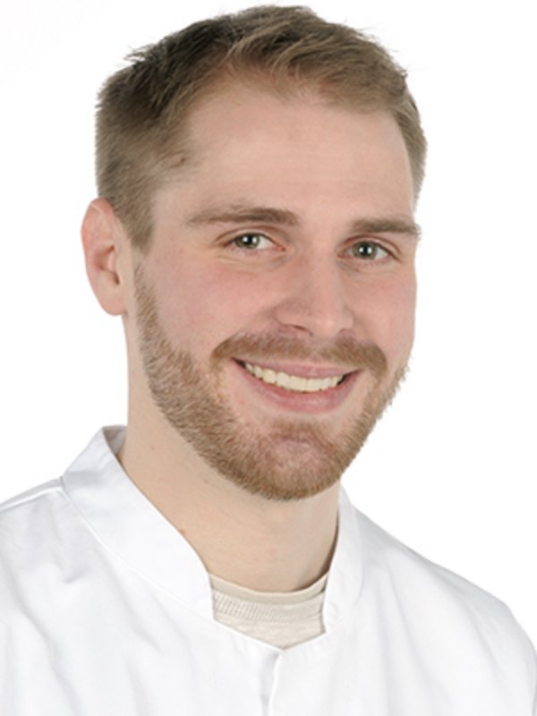 UKM Medizinische Klinik D | Lino Henkel | Er trägt einen weißen Kasack und lächelt in die Kamera.