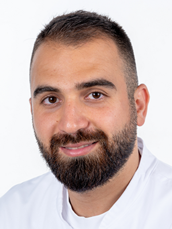 UKM | Portrait eines Zahnarztes der Klinik für Parodontologie. Er trägt einen weißen Kasack und lächelt.