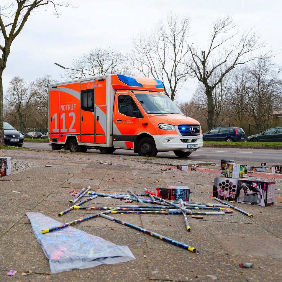 Symbolbild: Silvesterraketen auf dem Boden im Vordergrund, ein Rettungswagen mit der Aufschrift 112 im Hintergrund