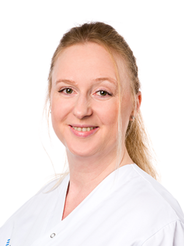 UKM | Portraitaufnahme einer Dentalhygienikerin der Klinik für Parodontologie. Sie trägt einen weißen Kasack und lächelt.